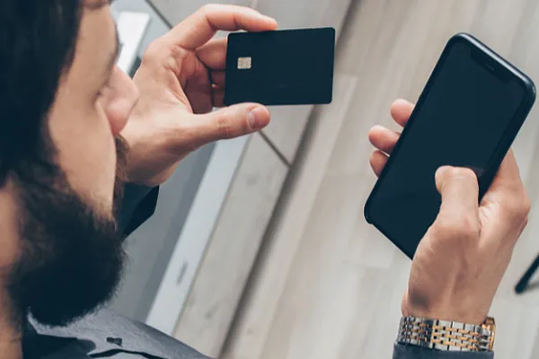 Man holding cellphone in one hand and credit card in the other.